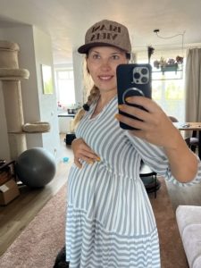 Selfie Frau mit Babybauch im gestreifter Tunika und Capy (7. Monat)