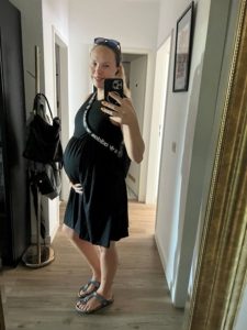 Selfie Frau mit Babybauch im schwarzen Sommerkleid (8. Monat)