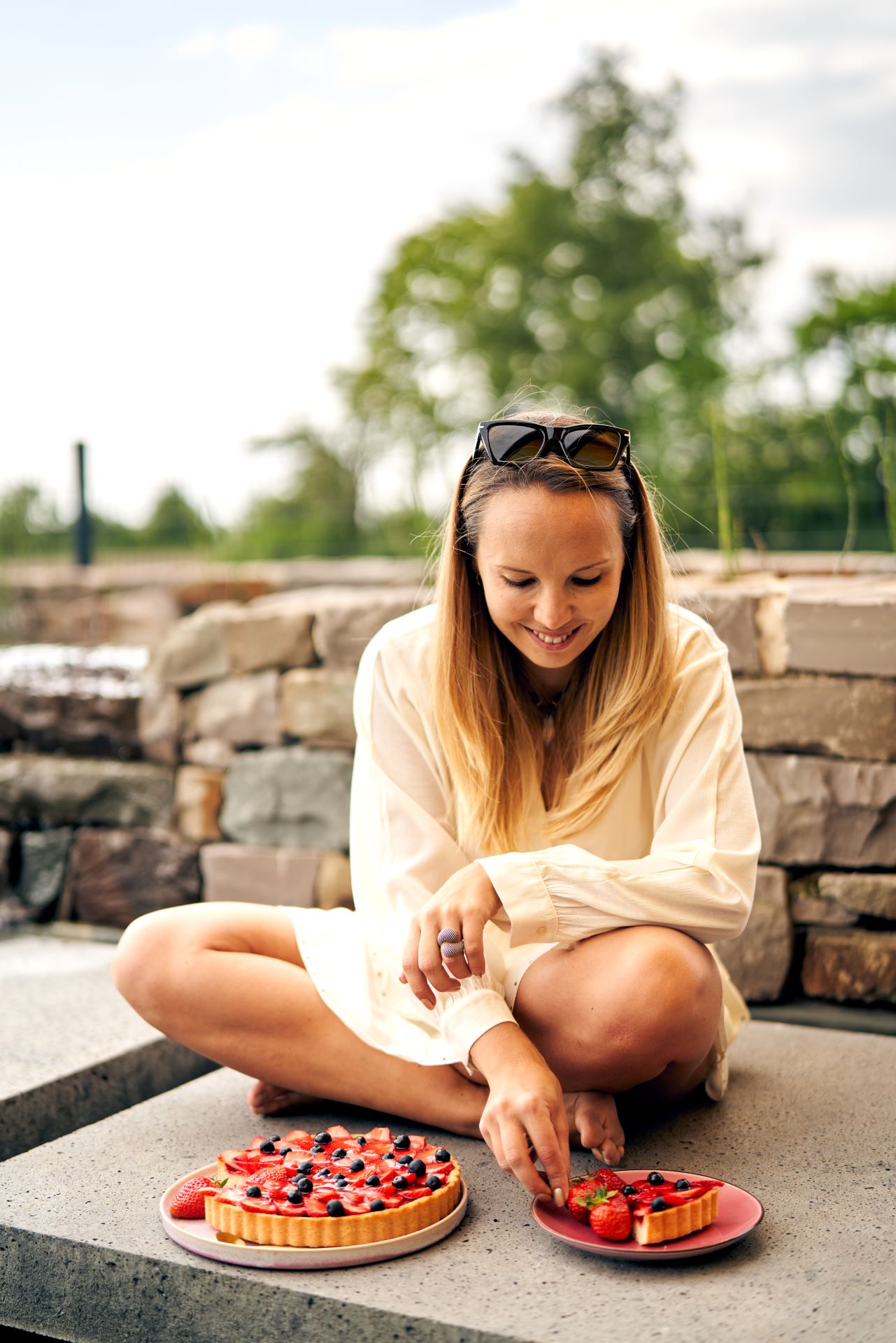 Frau im beigen Kleid genießt ein Stück Obstkuchen.